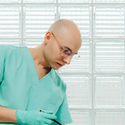 A nurse in scrubs reading a form by the window