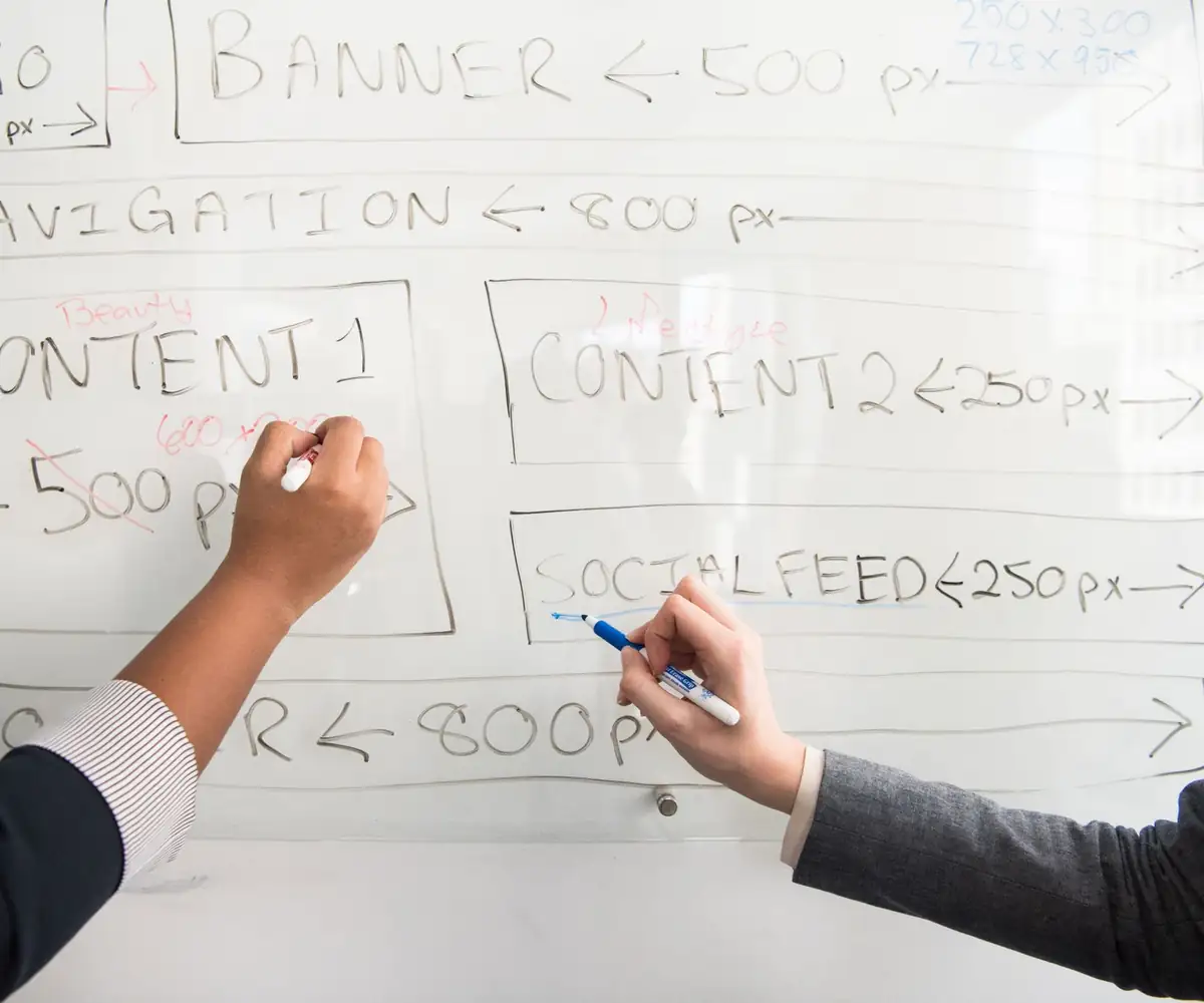 Two people sketching a website layout on a whiteboard
