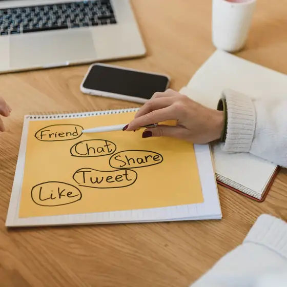 A social media plan being sketched beside a laptop and phone