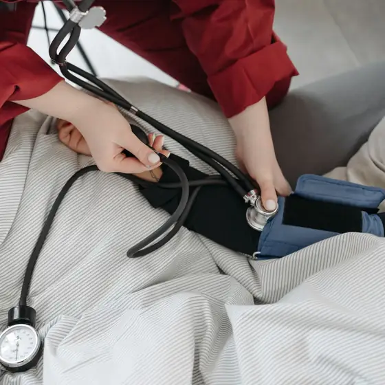 A nurse taking a patient’s blood pressure in bed at home
