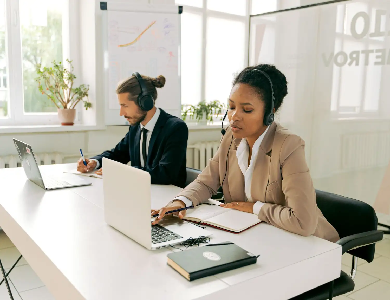 Two billing specialists with headsets working at their laptops
