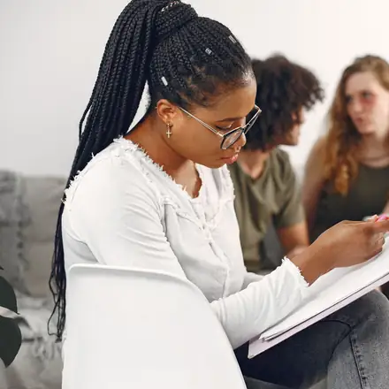 A therapist writing notes in a group session