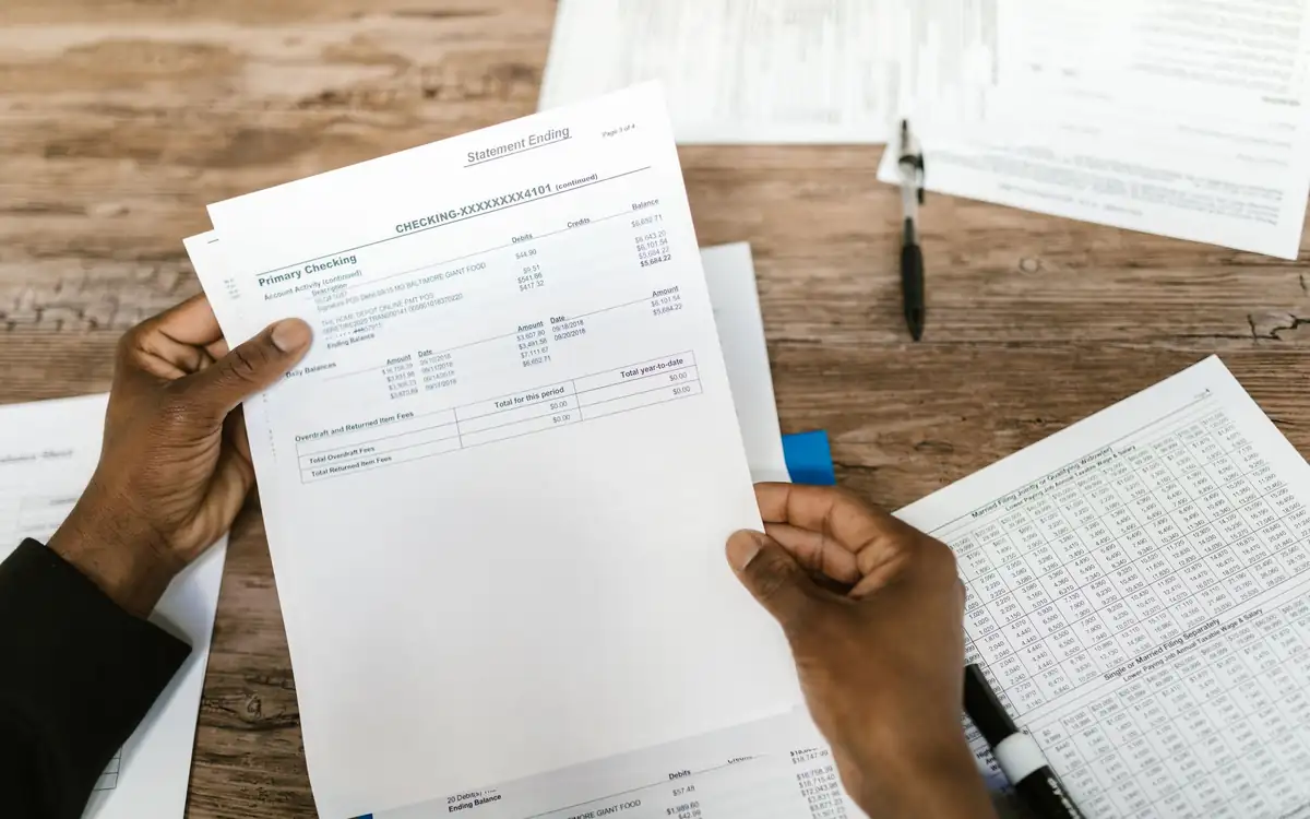 Hands holding a billing statement over a desk