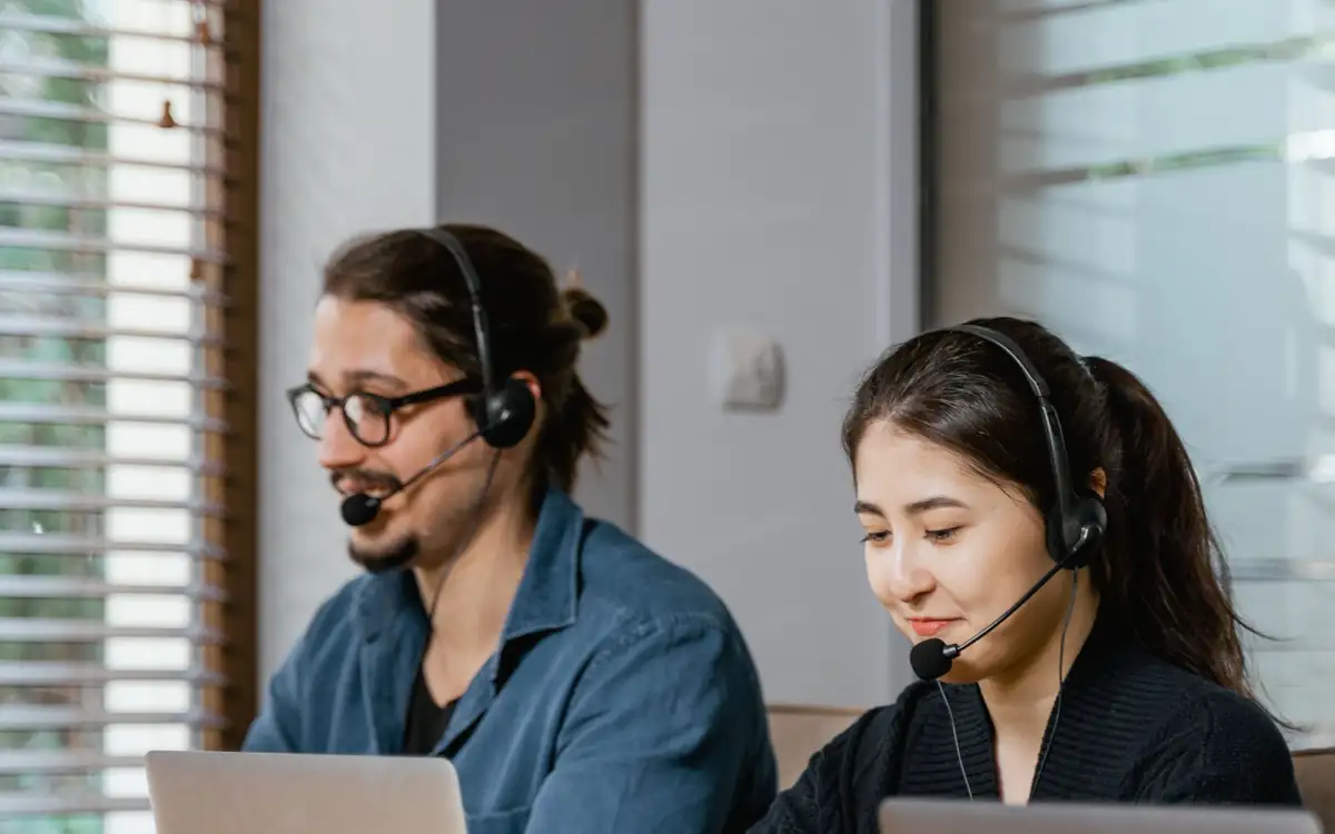Two specialists with headsets working at their laptops